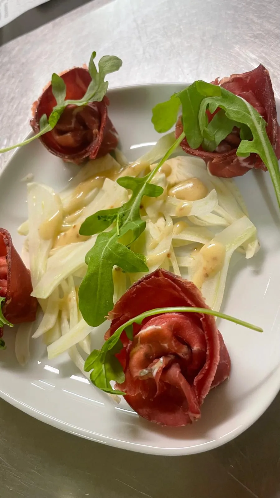 Tortelloni de bresaola roulés en rose, sur un lit de fenouil et roquette